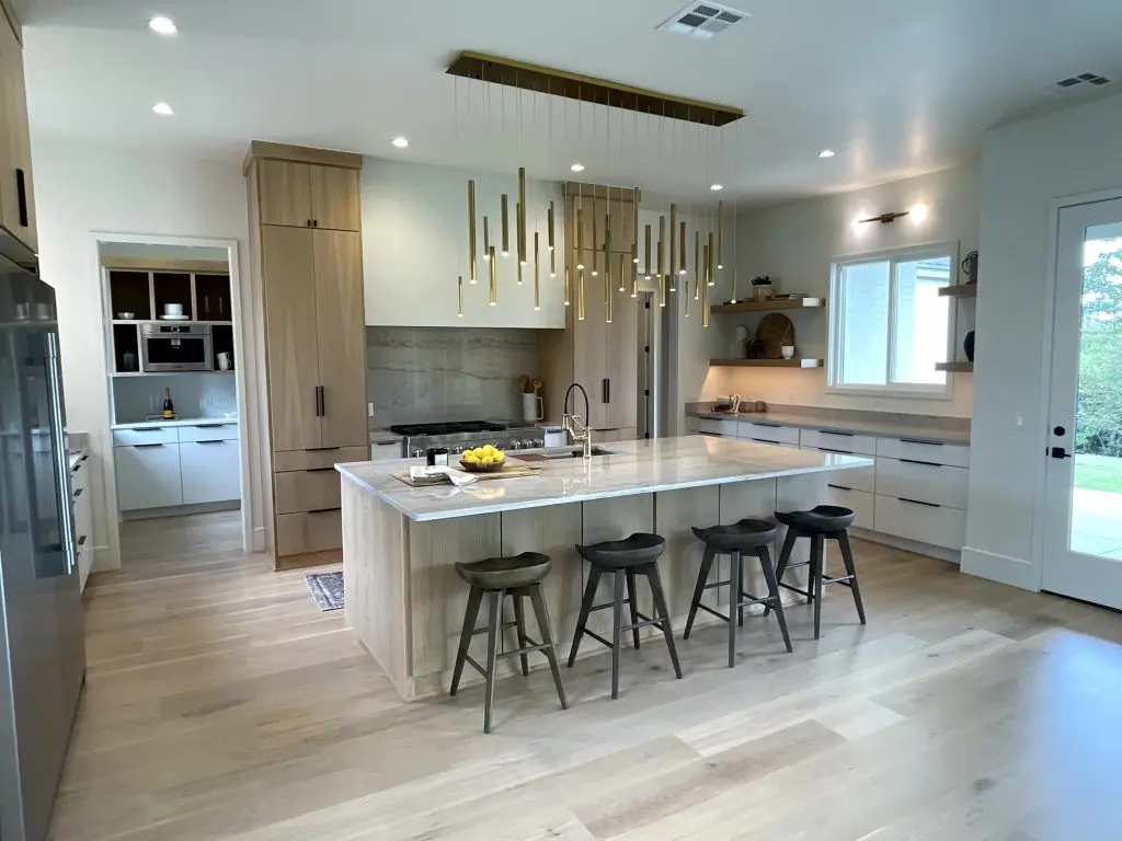 Modern kitchen with wood cabinetry, marble island, and gold pendant lighting in Newcastle, OK