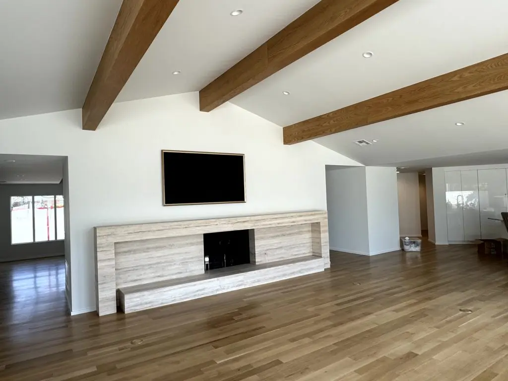Modern living room with wood beam ceiling and stone fireplace in Oklahoma City