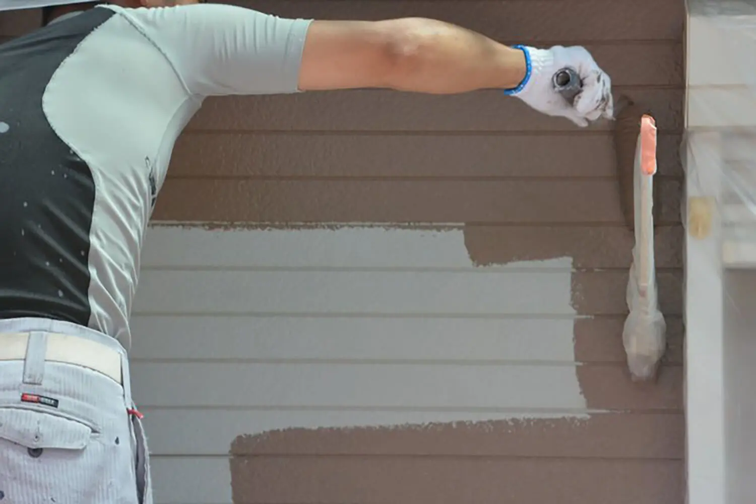 Painter applying extreme paint colors in Oklahoma weather to exterior siding, demonstrating coverage and durability during a professional exterior paint job