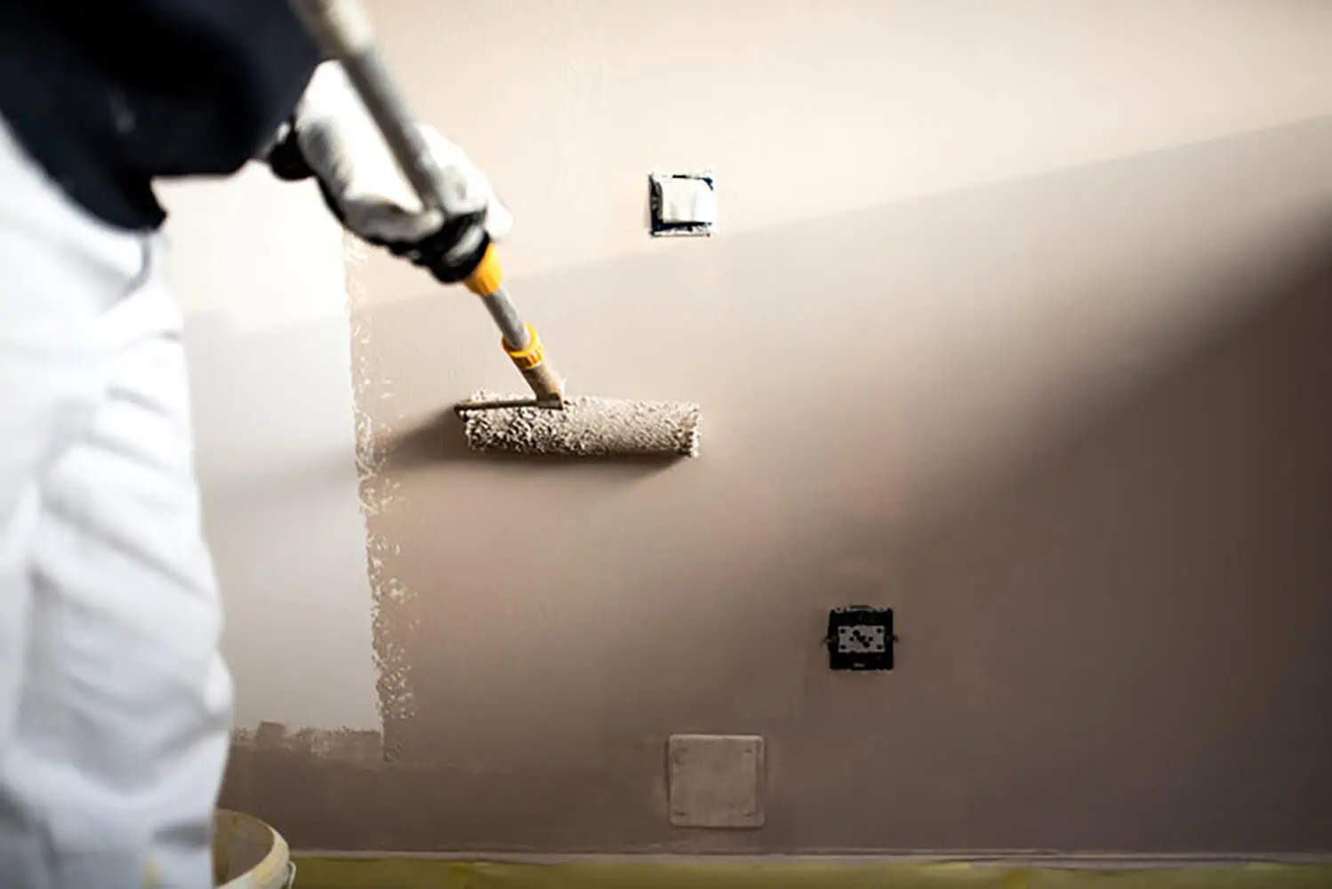 Professional painter applying wall paint during a project, illustrating how much does professional interior painting cost based on labor and prep work