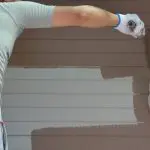 Exterior painter applying fresh paint to home siding during the best time of year for exterior painting in Oklahoma City