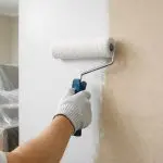 Interior wall being painted with a roller, showing how often should you repaint the interior of your home based on wall condition and wear
