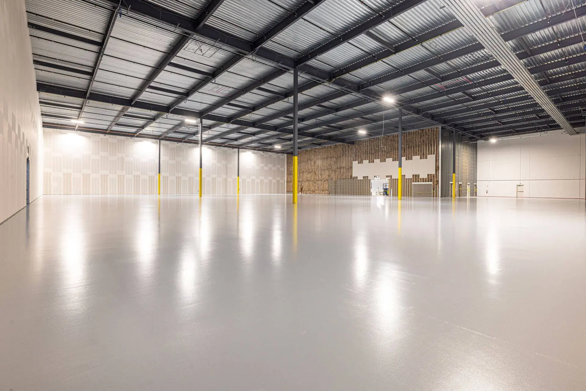 Freshly painted warehouse interior with light walls, gray coated floor, and exposed steel ceiling in Oklahoma City