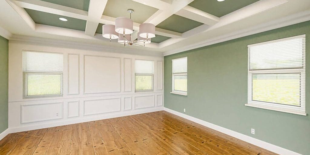Freshly painted living room with green walls and white trim, showing how interior paint finish choice affects maintenance and durability in everyday spaces