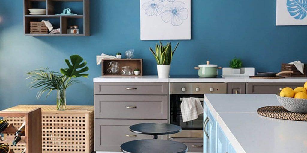 Modern kitchen with blue walls and clean surfaces, showing how to prepare your home for professional interior painting before painters arrive.